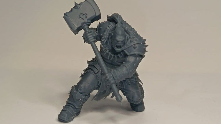 Gray figurine of a warrior holding a hammer on a beige background
