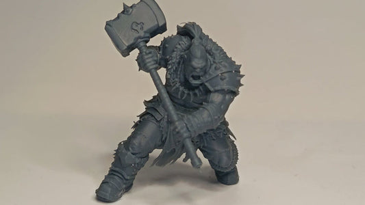 Gray figurine of a warrior holding a hammer on a beige background